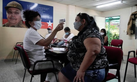 A woman has her temperature checked after receiving a dose of the Abdala vaccine at a vaccination center next to an image of Cuba’s former president Raúl Castro in Havana this month.