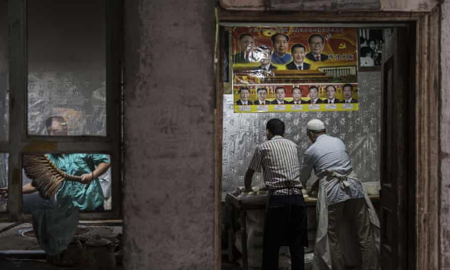 Uighur bakers in Kashgar, under a poster of Chinese leaders including Mao Zedong and Xi Jinping.