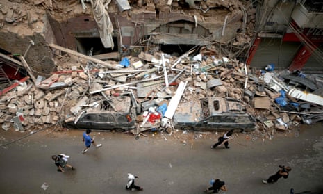People walk past a collapsed building in Beirut
