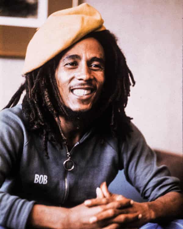 Bob Marley, grinning and hands clasped, in 1977
