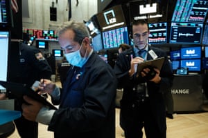 Traders, some in medical masks, work on the floor of the New York Stock Exchange last week. Traders are now trading remotely.