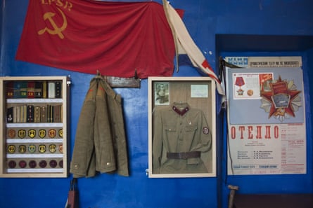 A Soviet Union flag and milaitary paraphernalia and uniforms on a blue wall
