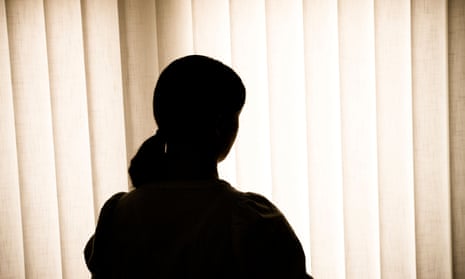 Silhouette of young woman against blind
