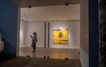 Seorang wanita mengambil gambar dengan ponselnya di ruangan putih dengan lukisan kuning besar