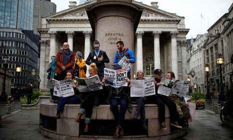 Extinction Rebellion protesters read mocked-up newspapers as they block the road at Bank in the City of London.