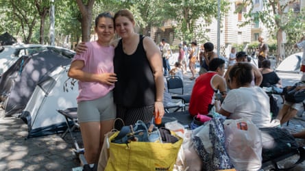 Petronela (right) and Nicoletta in urban landscape, tents in background