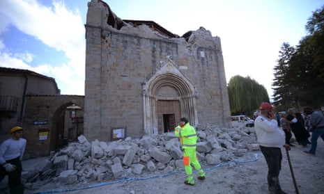 People stand in front of a damaged church in Amatrice