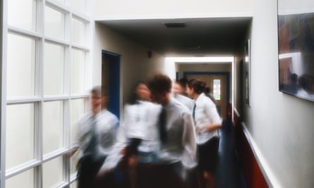 A motion blurred image of a group of pupils walking in the corridor at a secondary school