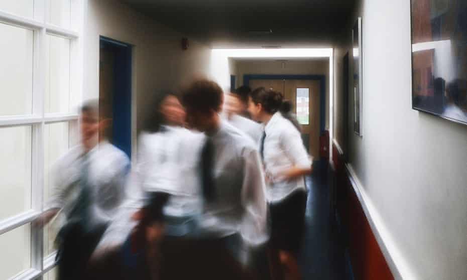 A motion blurred image of a group of pupils walking in the corridor at a secondary comprehensive