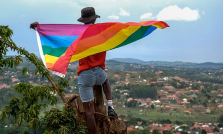 A gay Ugandan man holds a pride flag as he poses for a photograph