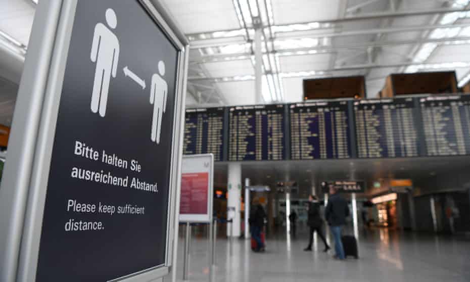 a sign at a German airport tells passengers to keep their distance from other people