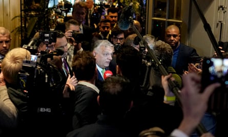 Orbán in the middle of a crowd of reporters and camera operators as he arrives for the National Conservatism conference