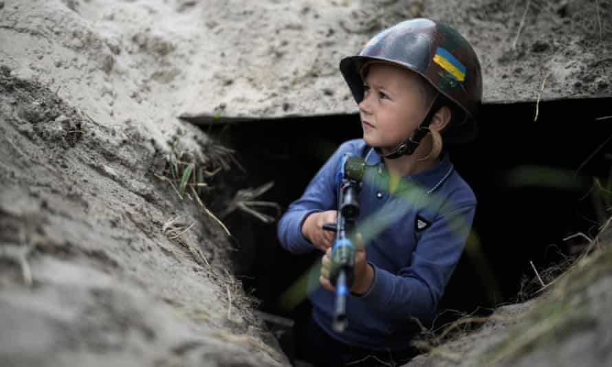 Ukrainian boy Valentyn 6, poses in the trench that he and his friend Andrii have dug at their makeshift checkpoint in their village next to a school crossing in Stoyanka, Ukraine.