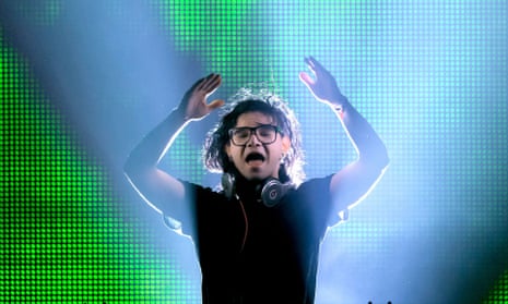 Skrillex … Standing up. And, in this case, raising his arms. 