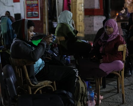 Sudanese refugees waiting on chairs at a bus station for return home.