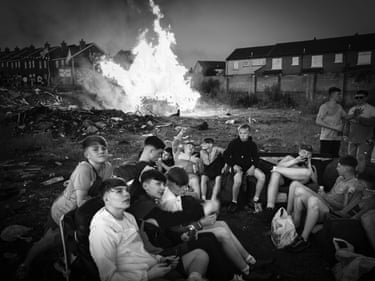 Teenage boys sit on armchairs near a bonfire