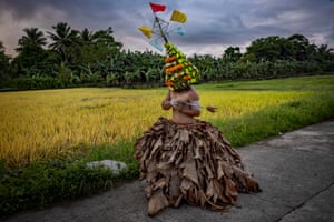 A man wearing dried banana leaves and a colourful headdresses whips his back in penitence