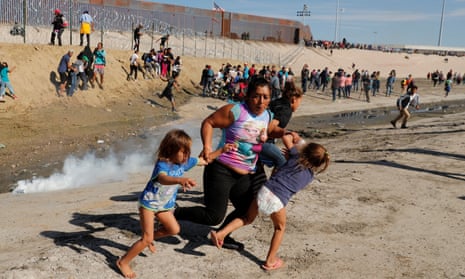 A migrant family run away from teargas in front of the Mexico-US border wall in Tijuana