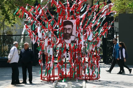 A black and white photo of Ayatollah Khamenei is surrounded by a large frame covered in Iranian national flags