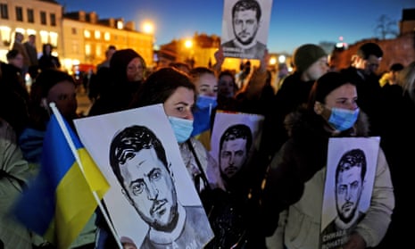 A crowd gathered to listen to US president Joe Biden in Warsaw hold up pictures of Ukrainian president Volodymyr Zelenskiy.