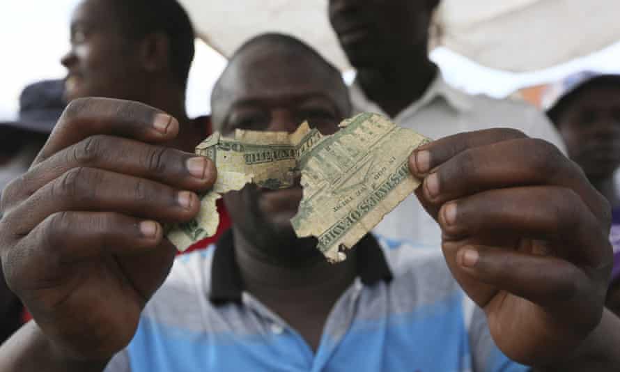 Albert Marombe holds up a tattered $20 bill