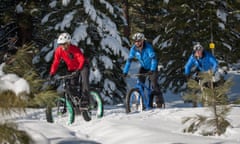 A trio of male riders in the snow on fatbikes: bicycles with extra wide, ridged tyres for cycling in extreme weather conditions.