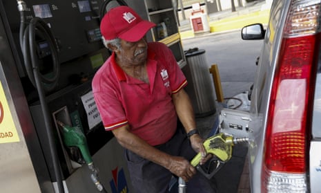 A worker pumps fuel into a vehicle at a gas station in Caracas, Venezuela