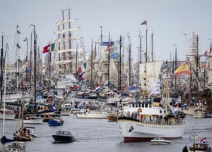 Dozens of tall ships and smaller vessels cluttered together in a harbour