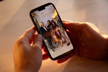 Someone holds a mobile phone with a photo of four smiling men and women on it.