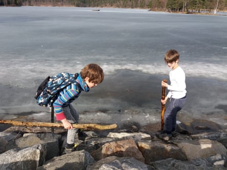 Two boys on the rocky shoreline of a frozen lake
