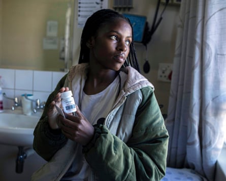 Thembelani Mbatha holds a bottle of pills in a medical room
