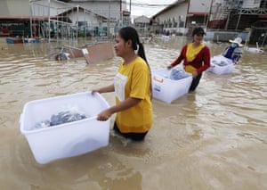 Garment workers gather clothes from a flooded factory in Phnom Penh, Cambodia