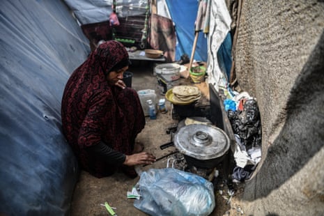 A woman cooks amid tents in a makeshift camp in Rafah.