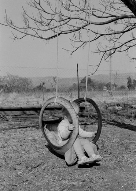 Black and white photograph of a little girl on a swing made of tyres