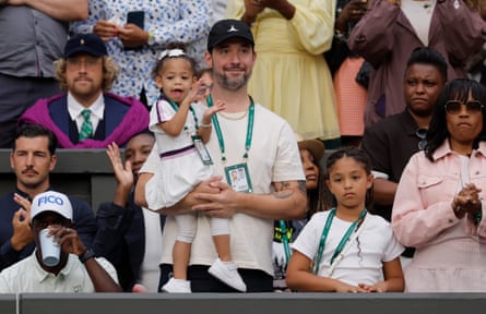 Alexis Ohanian, husband of Serena Williams, holds their youngest daughter Adira River Ohanian while their other daughter Alexis Olympia Ohanian Jr looks on as they wait in the players box before the Serena Williams v Maya Joint match on Centre Court.