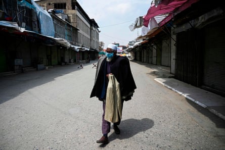 A man wears a face mask as he walks through a closed market in Kabul