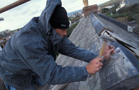 A workman nails flashing tiles on to a roof