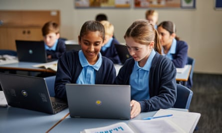 Two girls in a classroom working on laptops