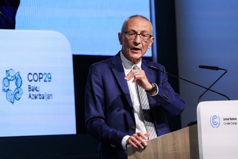 a man in a suit speaks into a microphone at a podium