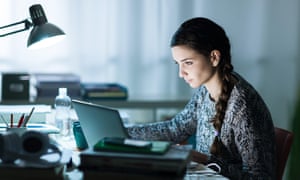 young female student sitting at desk and doing her homework.