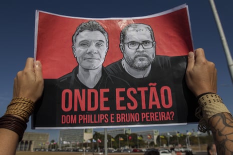 A person holds a sign with the images of two men on it and, written in Portuguese, 'Where are Dom Phillips and Bruno Pereira?'