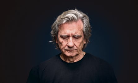 Griffin Dunne in black sweater against black background with eyes closed