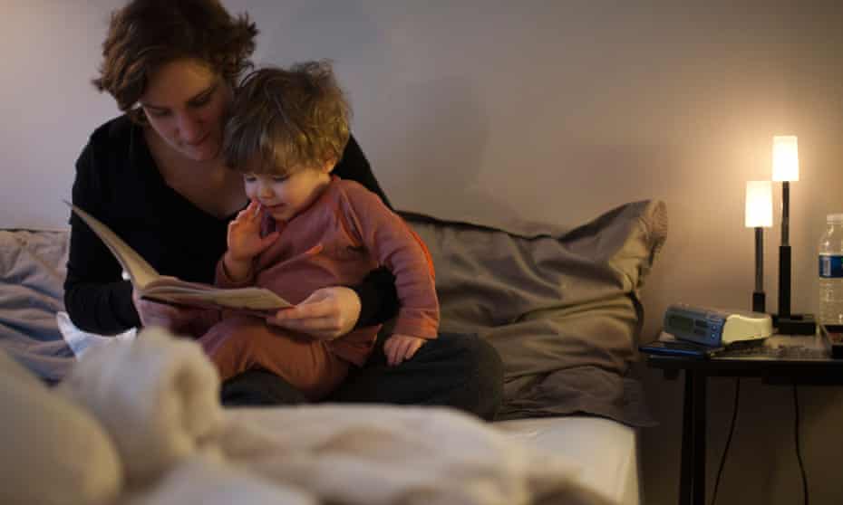 Mother holding toddler son on lap, reading bedtime story in bedC4TMHM Mother holding toddler son on lap, reading bedtime story in bed