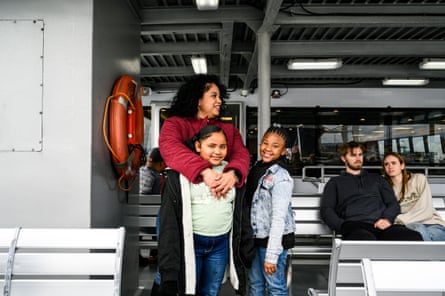 A woman and her children smile on a ferry as a couple look on in the background.