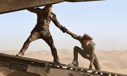 Action scene of Brolin helping Chalamet to his feet on what appears to be the loading ramp of a vehicle, in a desolate landscape