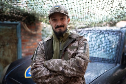 Dmytro Bezverbnyi sits on the bonnet of a car with his arms folded