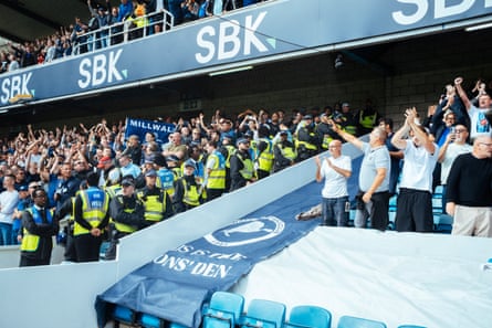 A West Ham fan gesticulates towards Millwall supporters across barrier blockaded by police