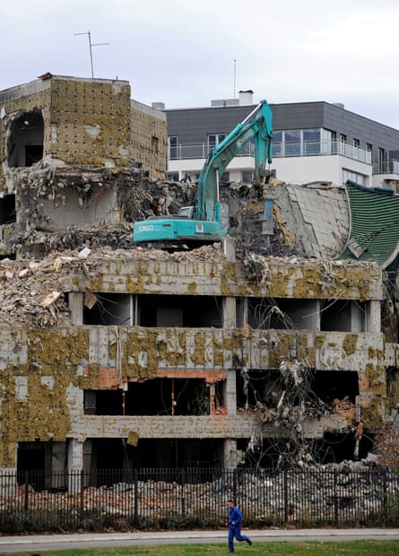 The bombed out wreck of a concrete building is being steadily demolished by one mechanical digger on the third floor.