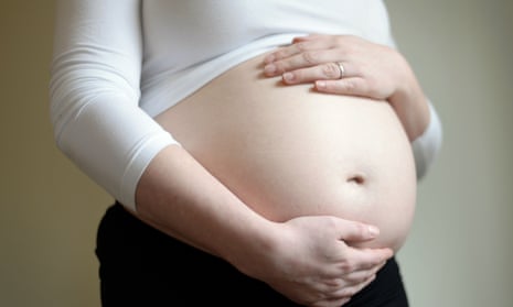 A pregnant woman cradles her stomach in her hands