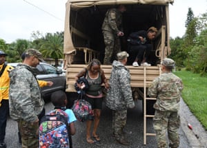 Residents exit a military vehicle after being rescued from their flooded homes by members of the Florida national guard in Orlando